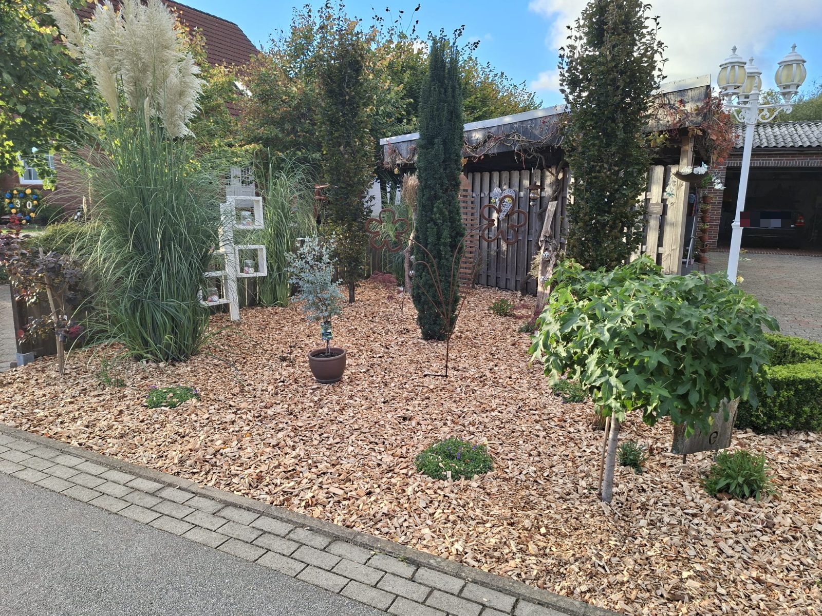 Vorgarten der Ferienwohnung Wiesmoor mit Pampasgras, Säulenbäumen und Laterne